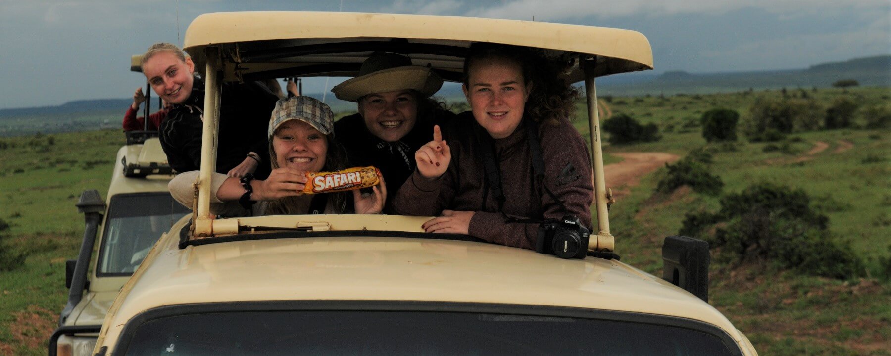 Elever i bil på safari viser frem pakke med Safari-kjeks
