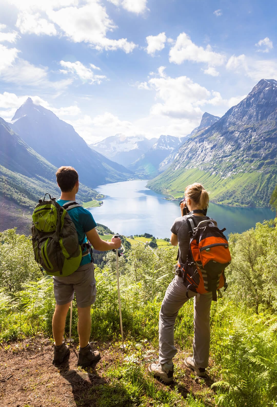Two hikers at viewpoint in mountains with lake, sunny summer – Sagavoll Folkehøgskole – Sagavoll Folkehøgskole To turgårere tar bilde av fjelltoppene og en innsjø