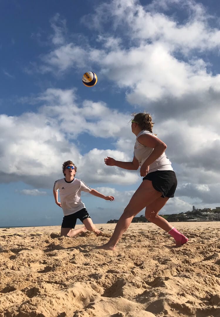 To elever spiller volleyball i sanden på stranden