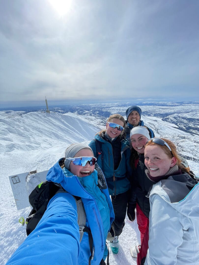 Fem personer tar selfie i snøen på toppen av et fjell