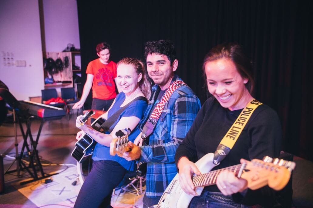 Tre elever som spiller gitar og ler