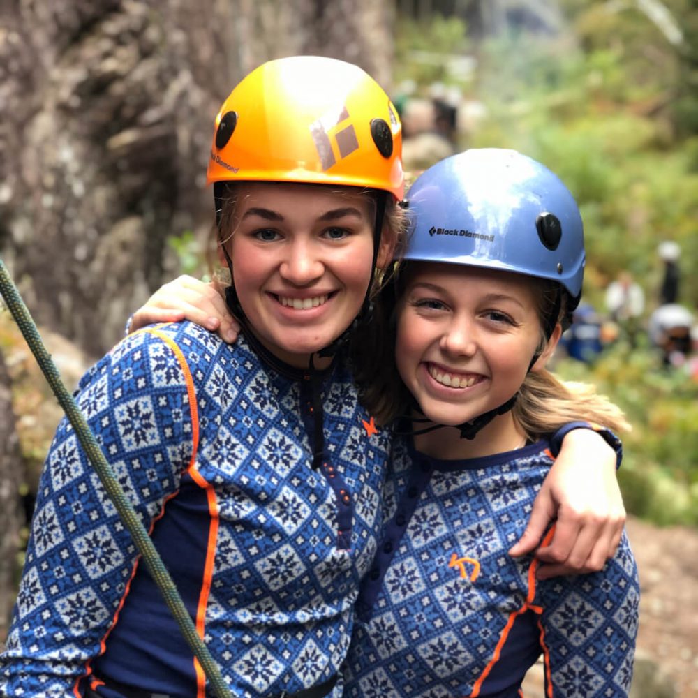 To jenter med hjelm som skal klatre i fjellet